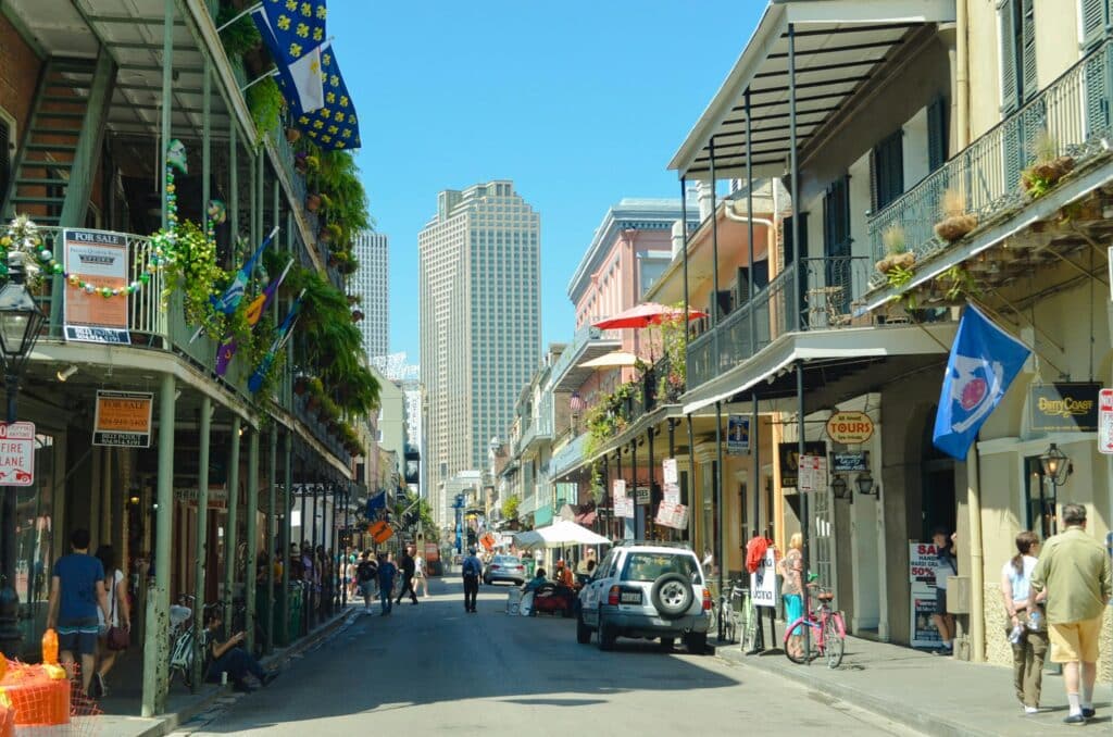 pexels photo 18462327 18462327 Explore a lively New Orleans street bustling with pedestrians, cars, and iconic architecture under a clear summer sky.